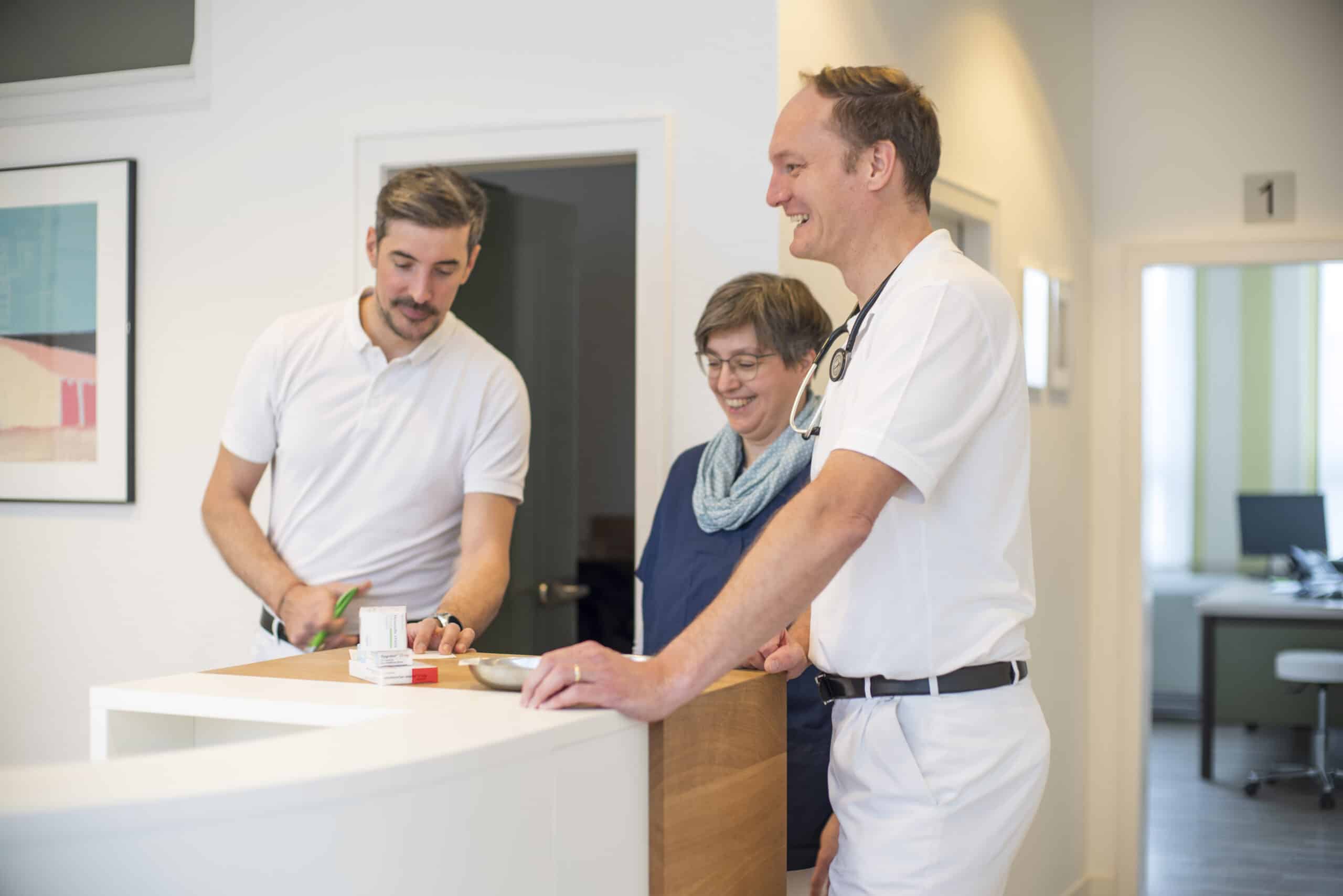 Ärzte beraten Patienten in einer modernen hausärztlichen Gemeinschaftspraxis.